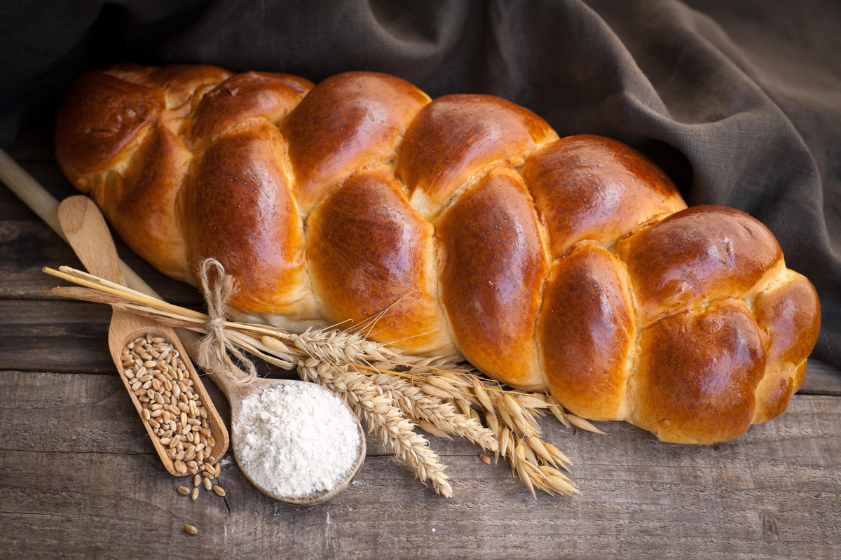 Brioche tréssée dorée accompagnée d'épis de blé et de farine
